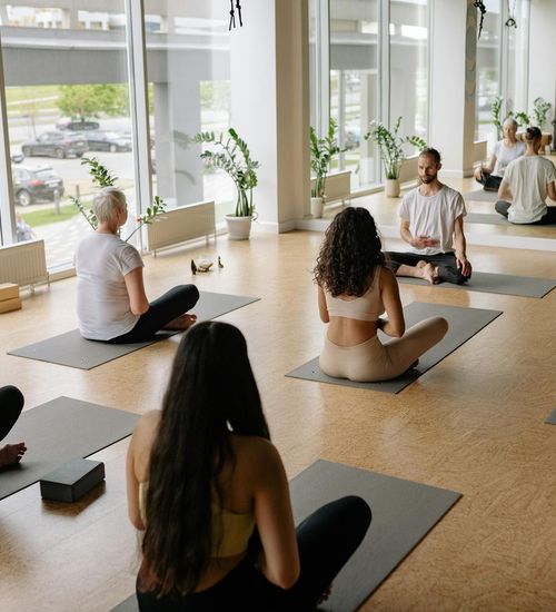 A diverse group of individuals practicing yoga together in a welcoming studio with neon ambient light.